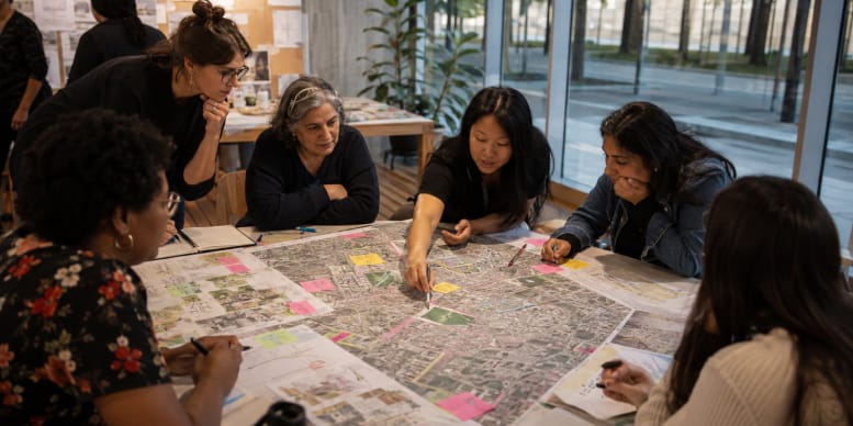 Group of women working around a large city map with notes and markers during an urban planning workshop.